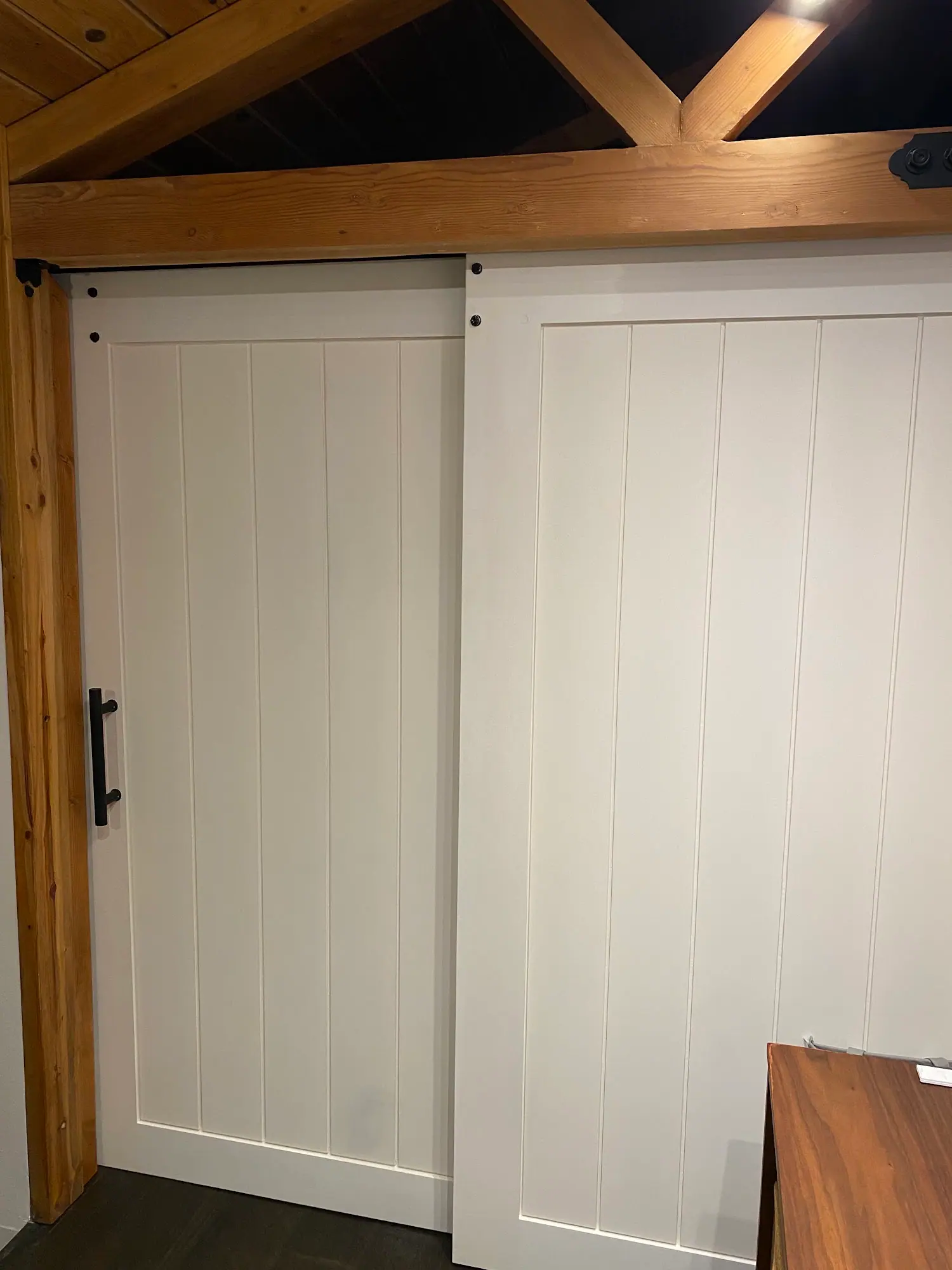 White sliding barn doors with a black handle and timber beams