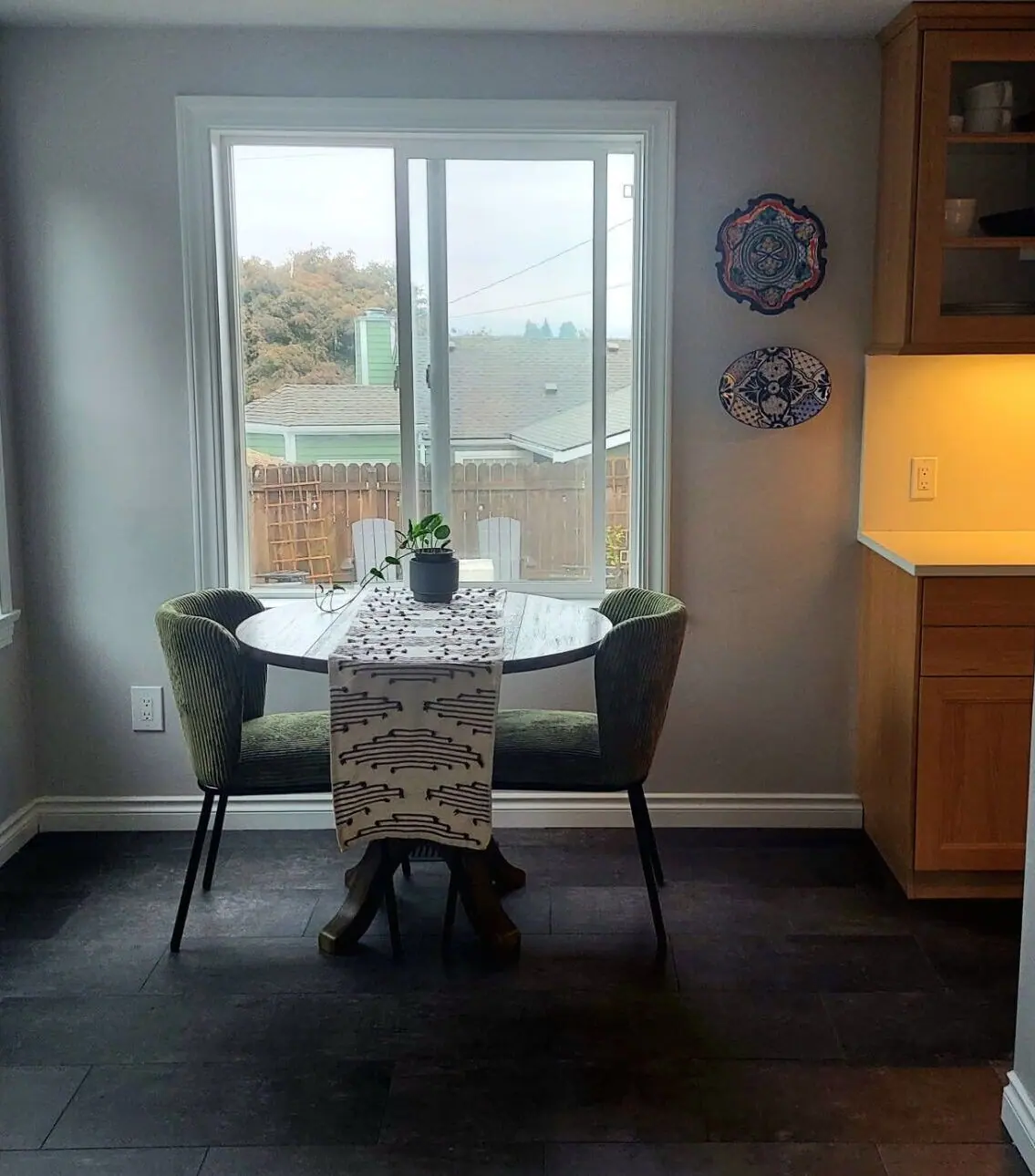 Dining nook with a round table, green chairs and a window