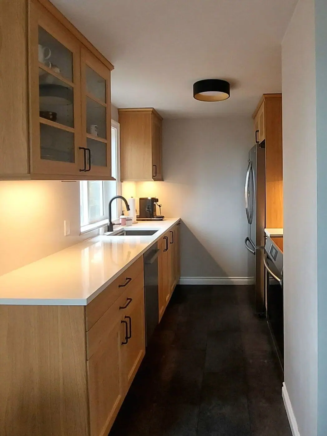 Galley kitchen with light wood cabinets and a white countertop